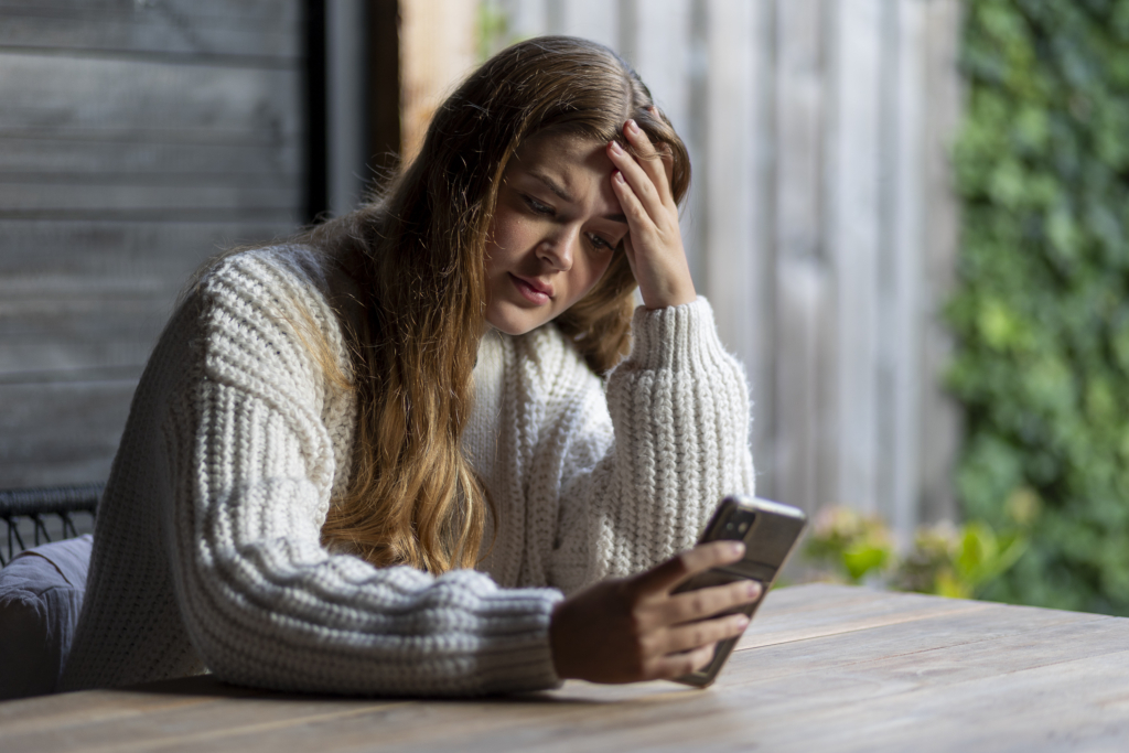 Meisje kijkt op telefoon. Afbeelding voor dossier cybercrime