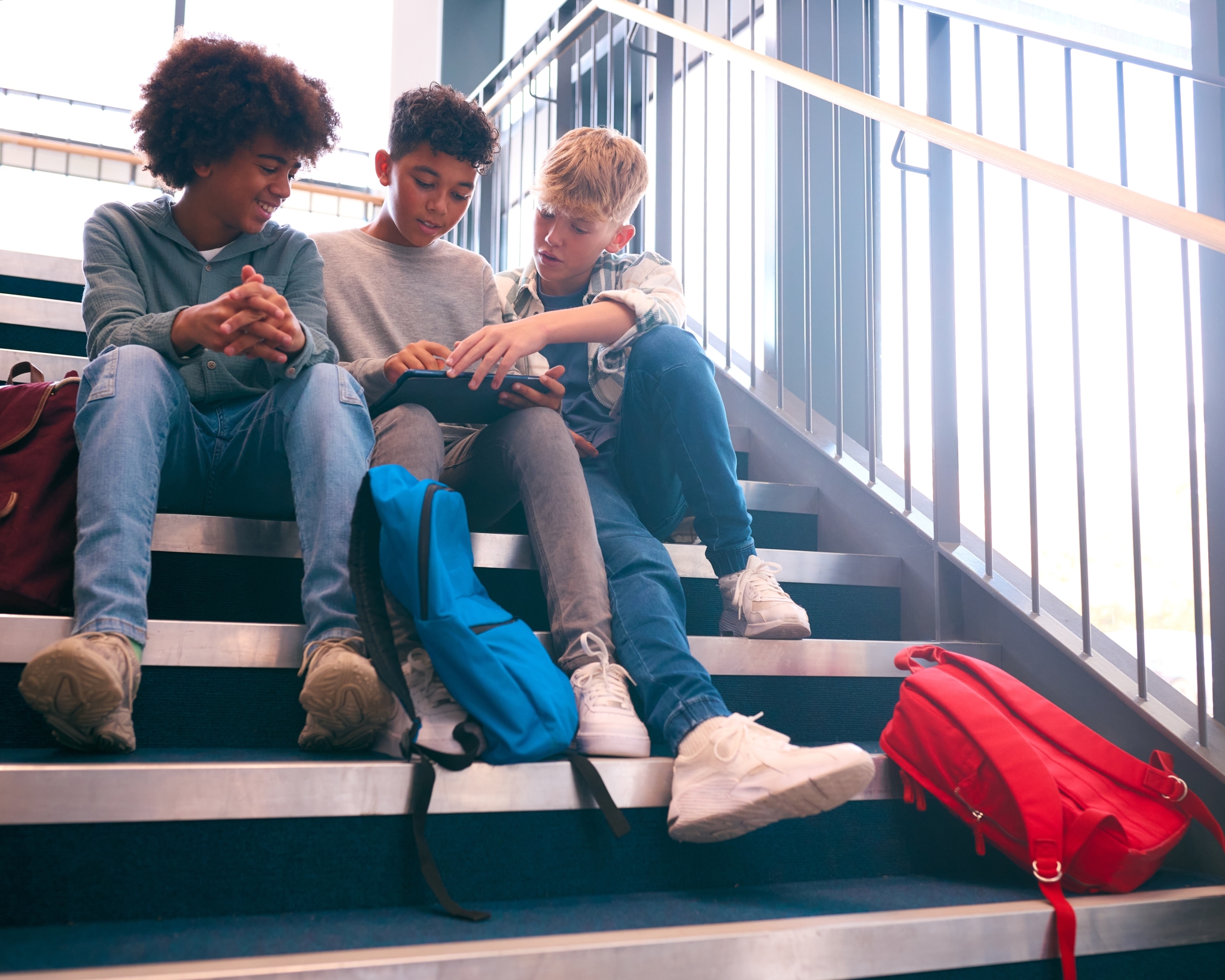 Een groepje jongeren zittend op de trap in school met hun mobiel.