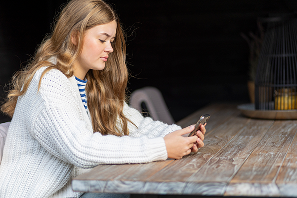 meisje aan tafel kijkt op telefoon